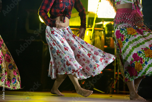 Young dancer woman barefoot in gypsy dress dancing on stage