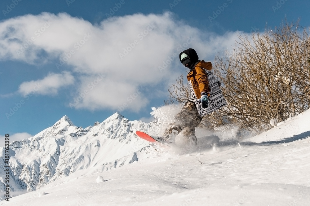 Portrait of snowboarder in sportswear jumping on the powder mountain slope