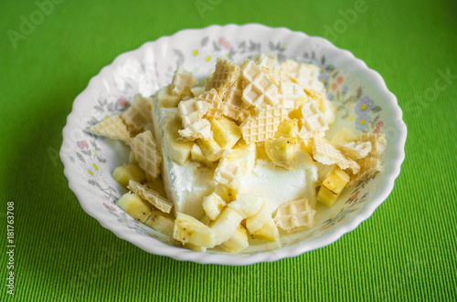 Vanilla ice cream in a plate with pieces of waffle