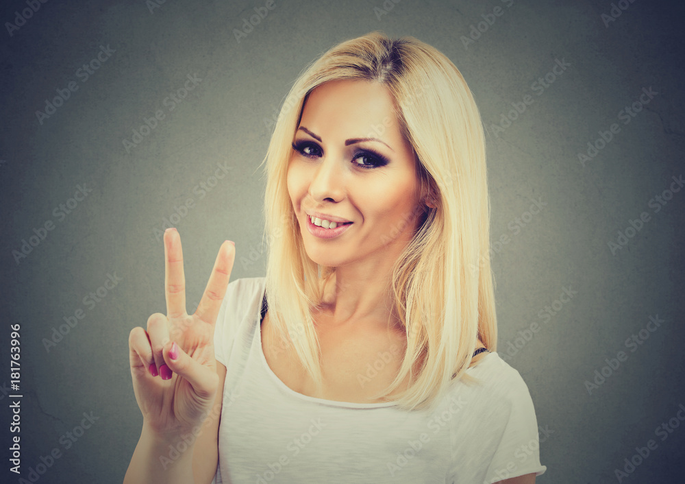 Smiling woman showing victory or peace sign isolated on gray background Smiling woman showing victory or peace sign isolated on gray background