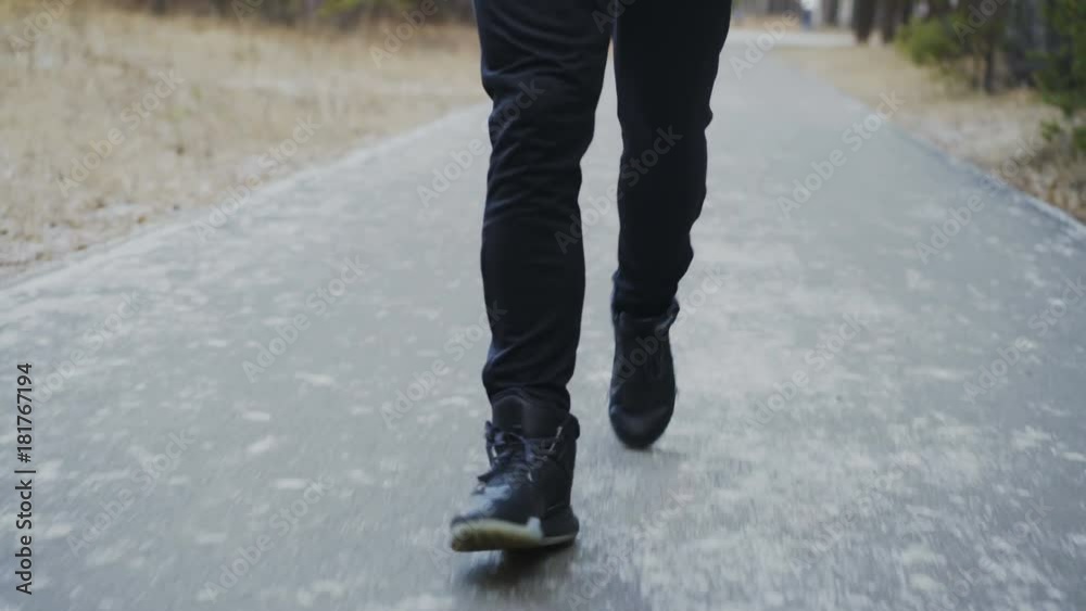 Tilt down shot of attractive runner man in headphones jogging while listening music in winter park in the morning Tilt down shot of attractive runner man in headphones jogging while listening music in winter park in the morning