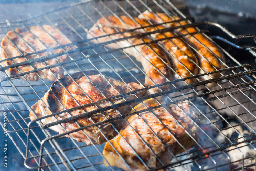 Meat and sausages are fried in a street grill, close-up