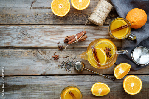Hot orange tea with spices on wooden rustic background 

