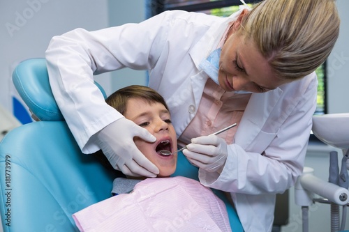 Dentist holding equipment while examining boy