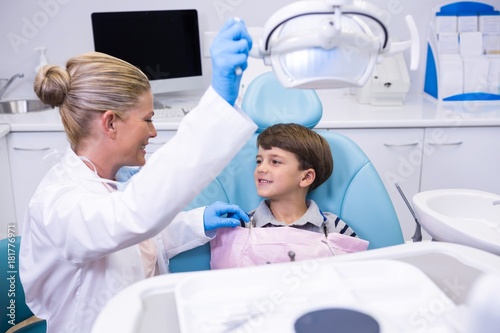 Side view of dentist adjusting electric light while boy sitting