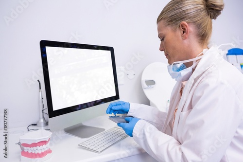 Side view of dentist working while sitting by computer