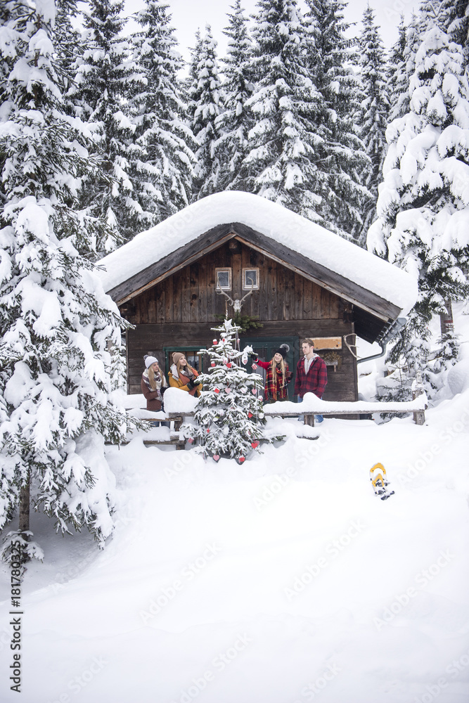 Austria, Altenmarkt-Zauchensee, friends decorating Christmas tree at wooden house Austria, Altenmarkt-Zauchensee, friends decorating Christmas tree at wooden house