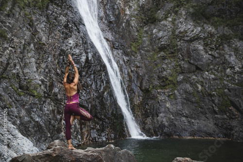 Italy  Lecco  woman doing Tree Yoga Pose on a rock near a waterfall