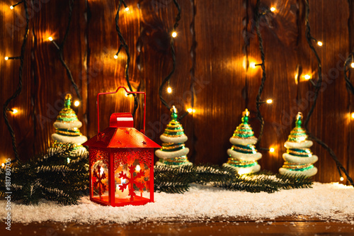 Christmas candle lantern and Christmas tree branches, snow, snowflake and decorations on bokeh background blurred lights. Free space