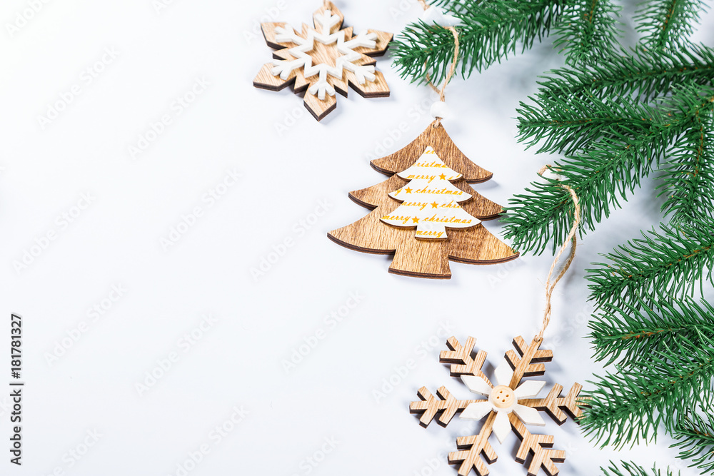 Christmas frame with the branches of the Christmas tree and wooden decorations on white background. Simple Christmas composition with free space Christmas frame with the branches of the Christmas tree and wooden decorations on white background. Simple Christmas composition with free space