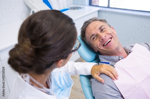 Patient sitting on chair while looking at dentist in medical