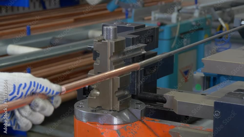 Bending of metal tubes on industrial machine in factory. Hands of worker bends product for refrigeration and ventilation equipment and air conditioners. Modern technologies.