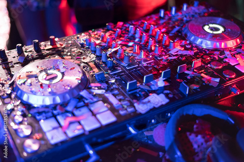 The DJ console cd mp4 deejay mixing desk Ibiza house music party in nightclub with colored disco lights.