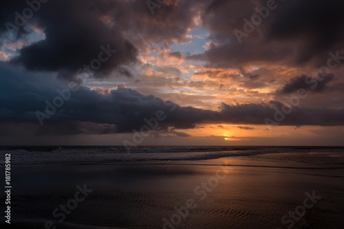 Dramatic sunset clouds reflected on the water sea. Tropical beach landscape at golden hour © Ivan Kurmyshov