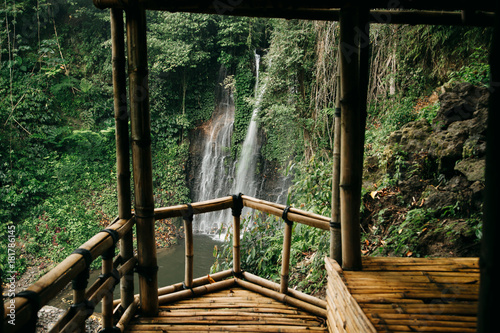 Beautiful waterfall in green forest. View from bamboo wooden house. Nature landscape background