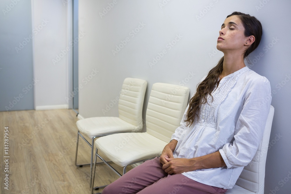 Sad patient with eyes closed sitting on chair at hospital Sad patient with eyes closed sitting on chair at hospital
