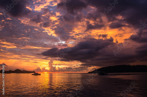 A fiery sun is setting in the bay of Kota Kinabalu, Borneo, colorizing the cloudy sky in a dramatic fashion © Rasmus