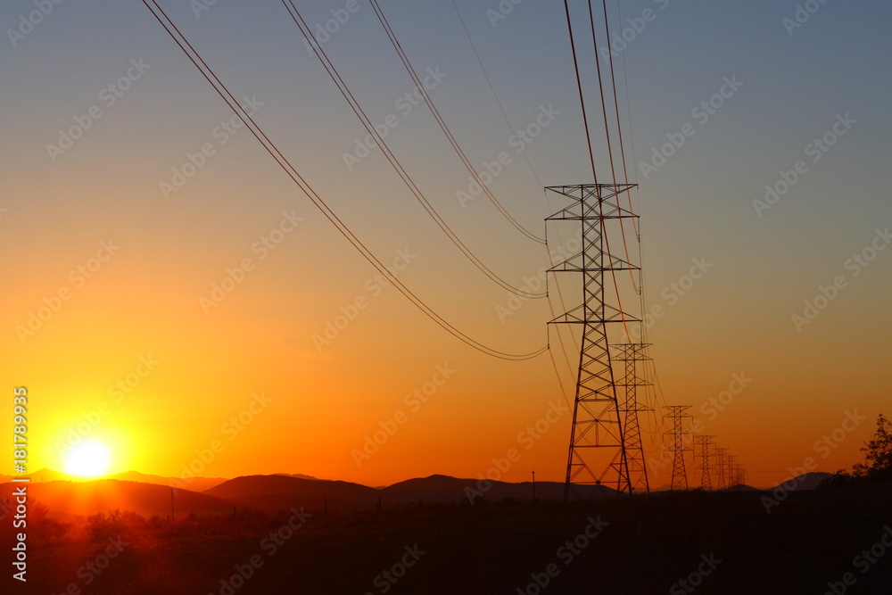High-power electric distribution tower with the setting sun in the background High-power electric distribution tower with the setting sun in the background