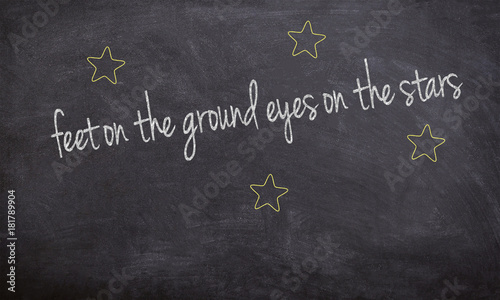 feet on the ground eyes on the stars chalk handwritten text on a black board with stars