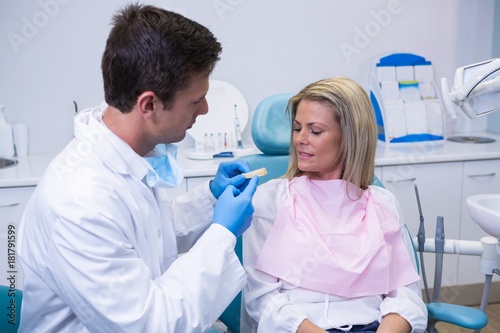 Side view of young doctor showing dental mold to patient