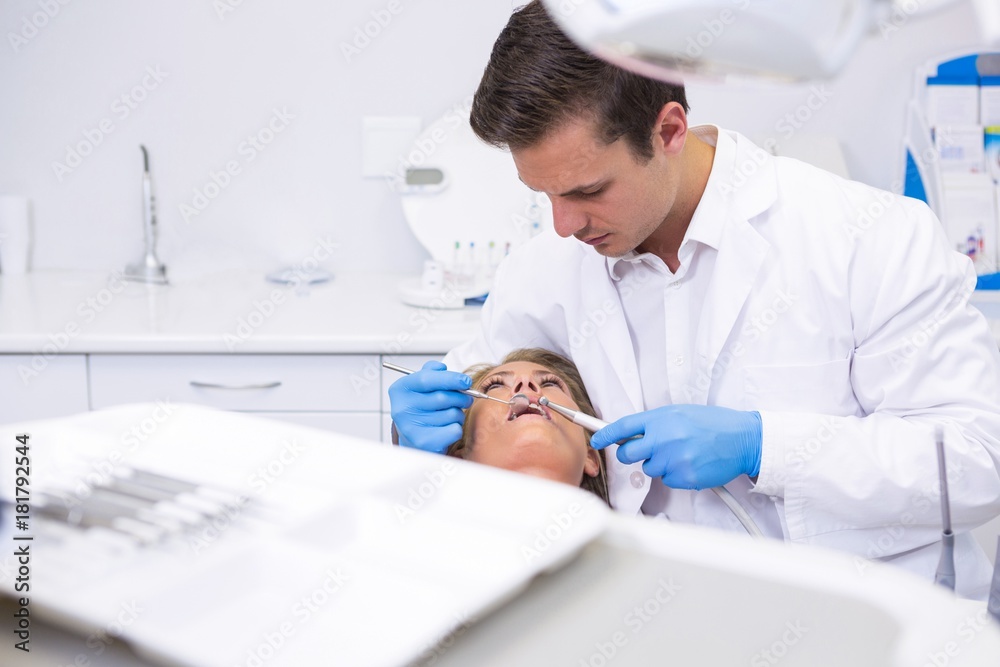 Dentist holding medical equipment while giving treatment to