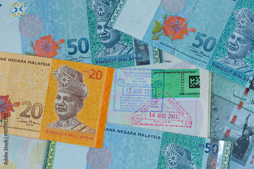 Malaysian Ringgit (MYR), different Malaysia dollar banknote money on passport with tourist visa, arrival departure stamp. photo