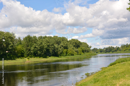 beautiful summer fairy tale, a bright summer natural landscape, the Dvina river against a blue sky with white clouds