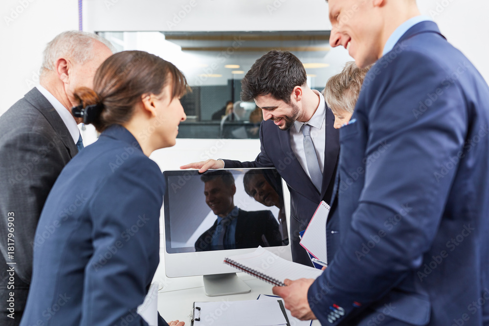 Geschäftsleute stehen um Computer Monitor im Büro Geschäftsleute stehen um Computer Monitor im Büro