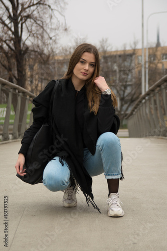 Young girl with winter coat in city on bridge