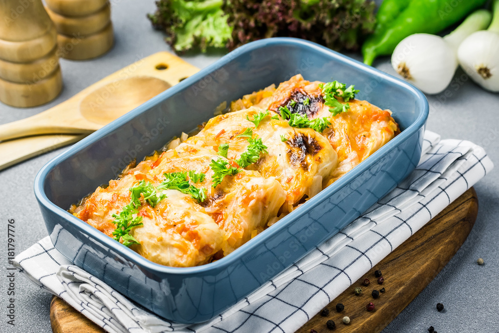 Vegetarian lentil stuffed cabbage rolls in a baking dish with ingredients. Selective focus, close up.