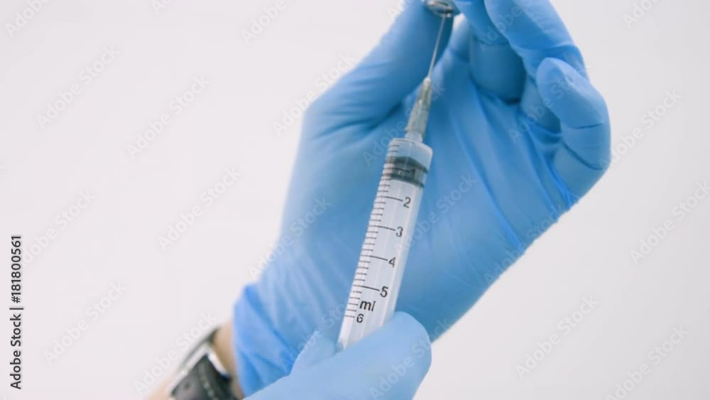 the hand of a doctor or a nurse in rubber gloves is typed physiological saline into a syringe