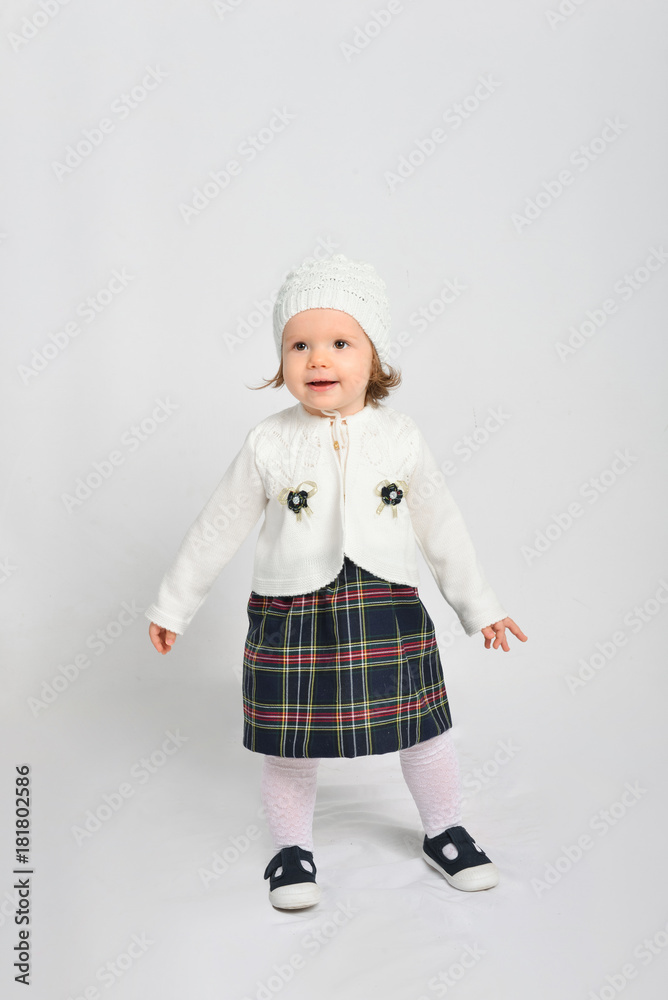 Little girl in a cap and sweater. Isolated on a gray background. Little girl in a cap and sweater. Isolated on a gray background.