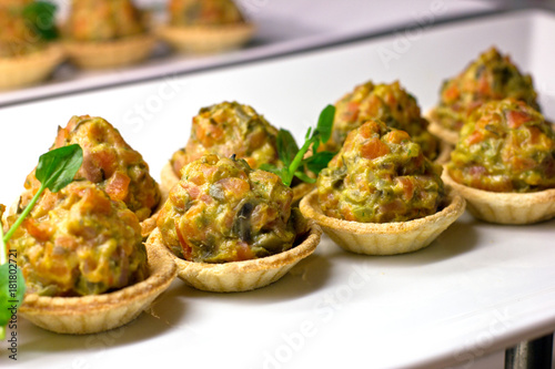 Tartlets with baked vegetables and herbs on a white porcelain dish