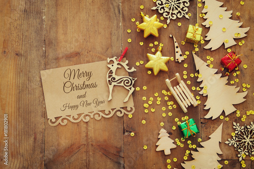 Top view image of christmas festive decorations next to note on old wooden background.