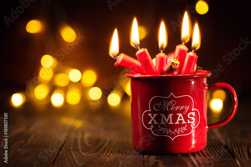 Burning candles in red mug