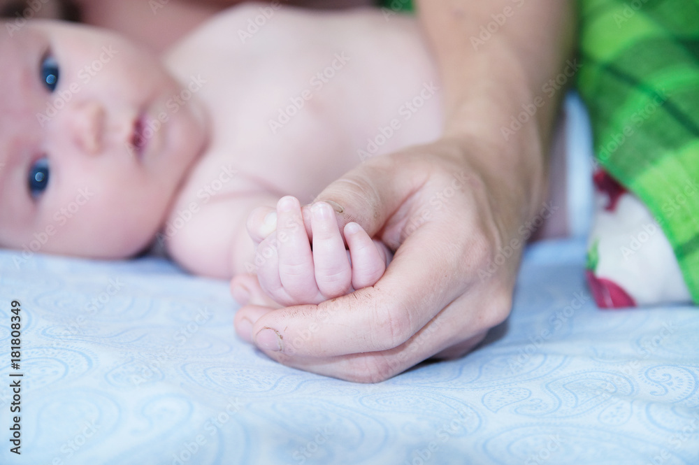Father holding baby hands, dad and infant lying together on bed Father holding baby hands, dad and infant lying together on bed