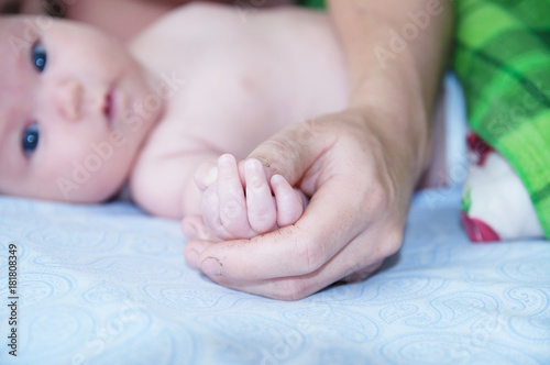 Father holding baby hands, dad and infant lying together on bed © aynur_sh