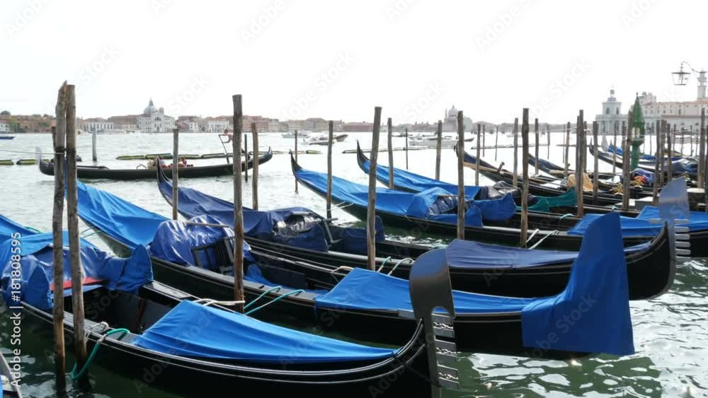 VENICE, ITALY, SEPTEMBER 7, 2017: Venetian gondola covered in blue cloth while docking on the canal in Venice Italy, Noses moored gondolas VENICE, ITALY, SEPTEMBER 7, 2017: Venetian gondola covered in blue cloth while docking on the canal in Venice Italy, Noses moored gondolas
