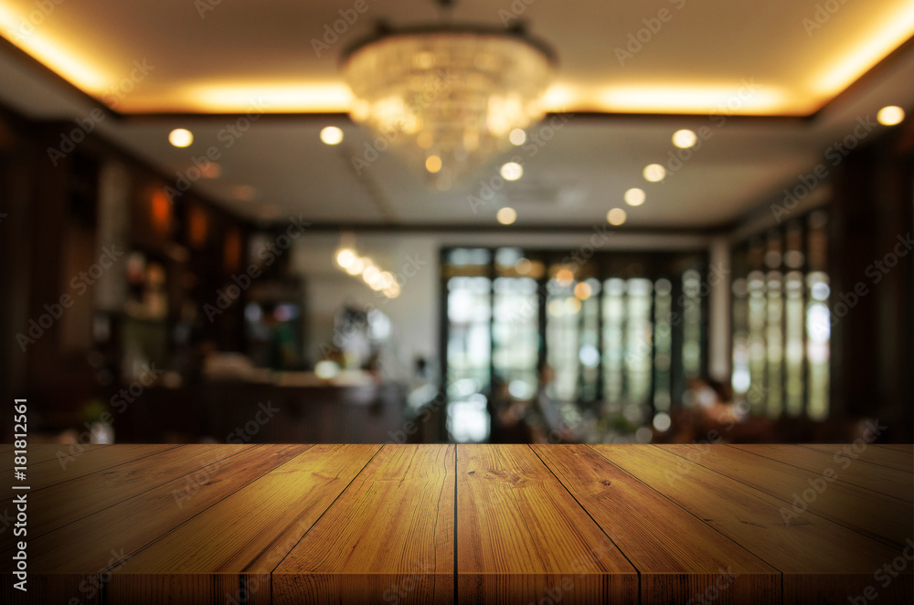 Wooden table top with blur coffee shop or restaurant interior background. Abstract background can be used product display.