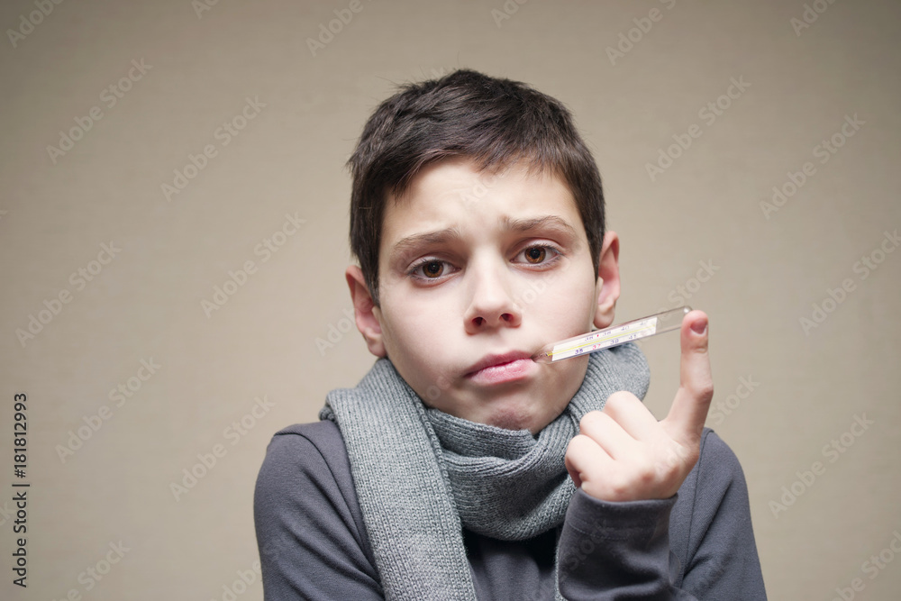 Obraz premium Boy's portrait in a warm scarf and with the thermometer in a mouth, close up. Medicine, health.