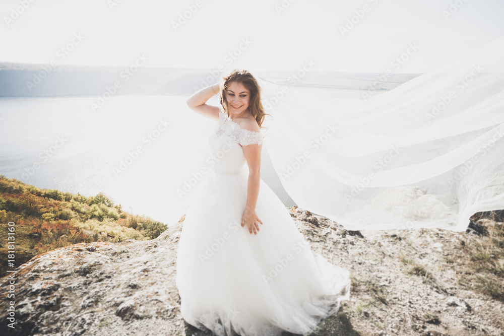 Romantic beautiful bride in white dress posing on the background sea