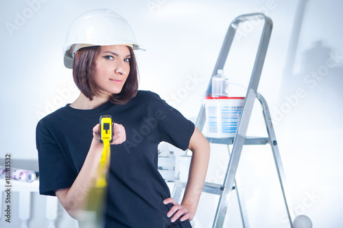 Girl builder. A girl in a construction helmet with a tape measure in her hand.