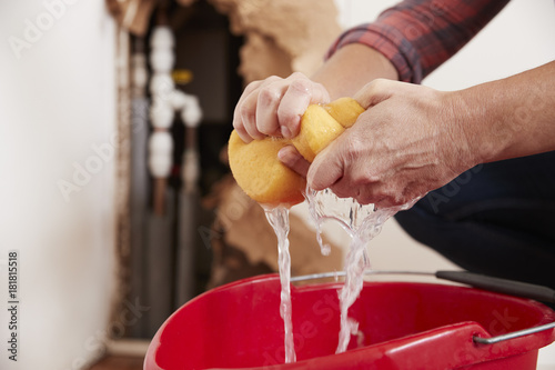 Woman wringing water out of a sponge into a bucket, detail photo