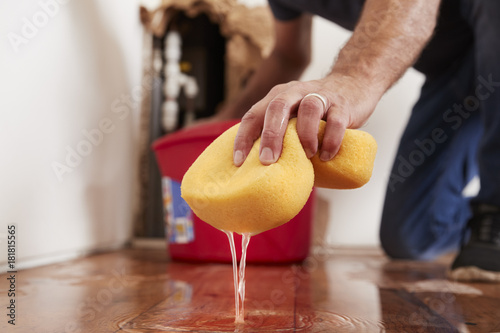Man mopping up water from the floor with a sponge, detail photo