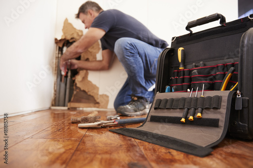 Middle aged man repairing burst pipe,plumbing, focus on foreground photo