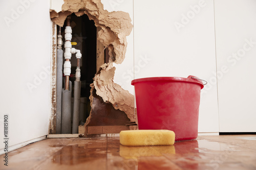 Damaged wall, exposed burst water pipes, sponge and bucket