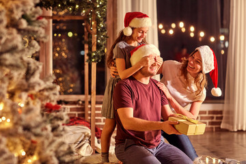 The family gives presents in a room with a Christmas tree on Christmas Day.