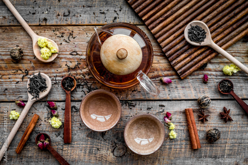 Tea party set. Tea pot, cups, dried tea leaves, fllowers, spices on wooden background top view Tea party set. Tea pot, cups, dried tea leaves, fllowers, spices on wooden background top view