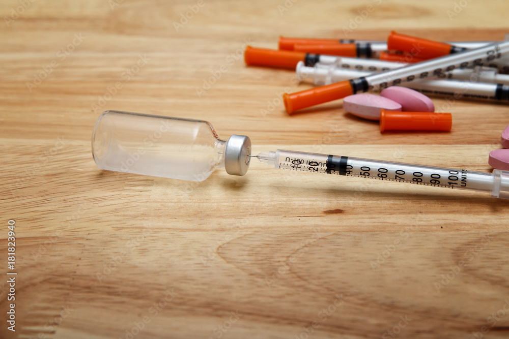Medical syringe and bottle of potion on wooden desk