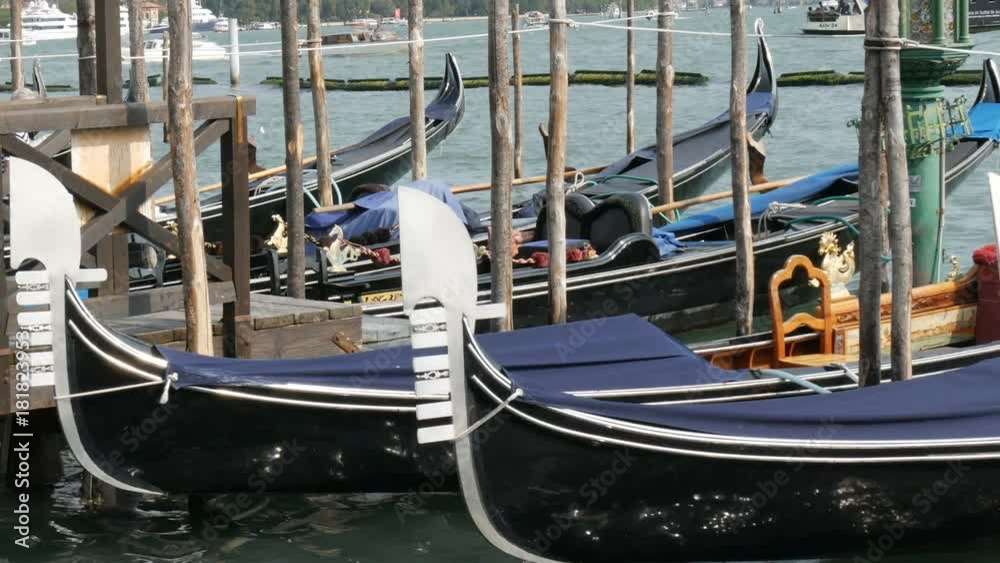 Venetian gondola covered in blue cloth while docking on the canal in Venice Italy, Noses moored gondolas neatly standing in a row Venetian gondola covered in blue cloth while docking on the canal in Venice Italy, Noses moored gondolas neatly standing in a row